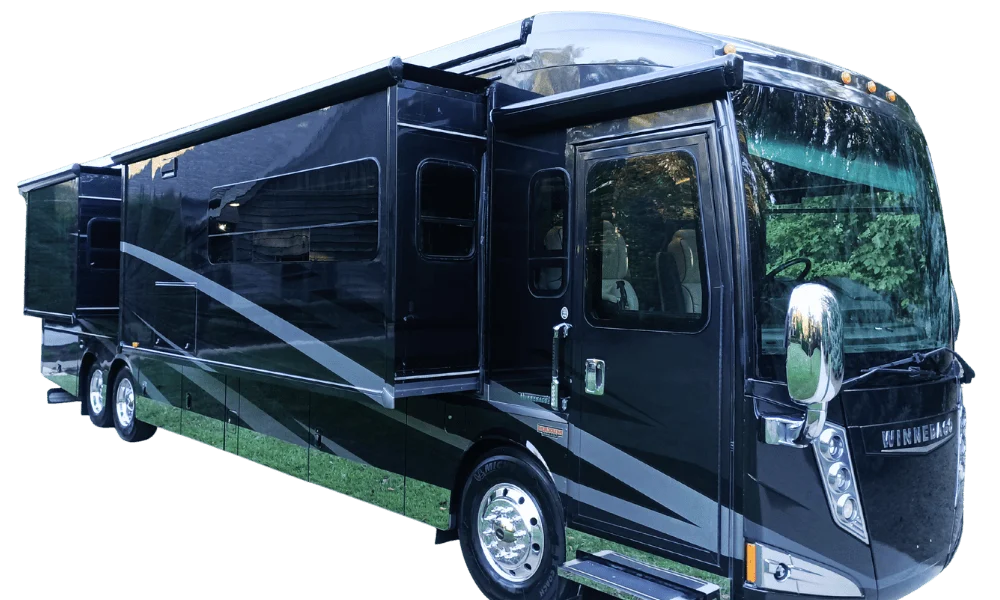 Sleek black motorcoach with extended side sections, reflecting trees, showcasing modern RV design.