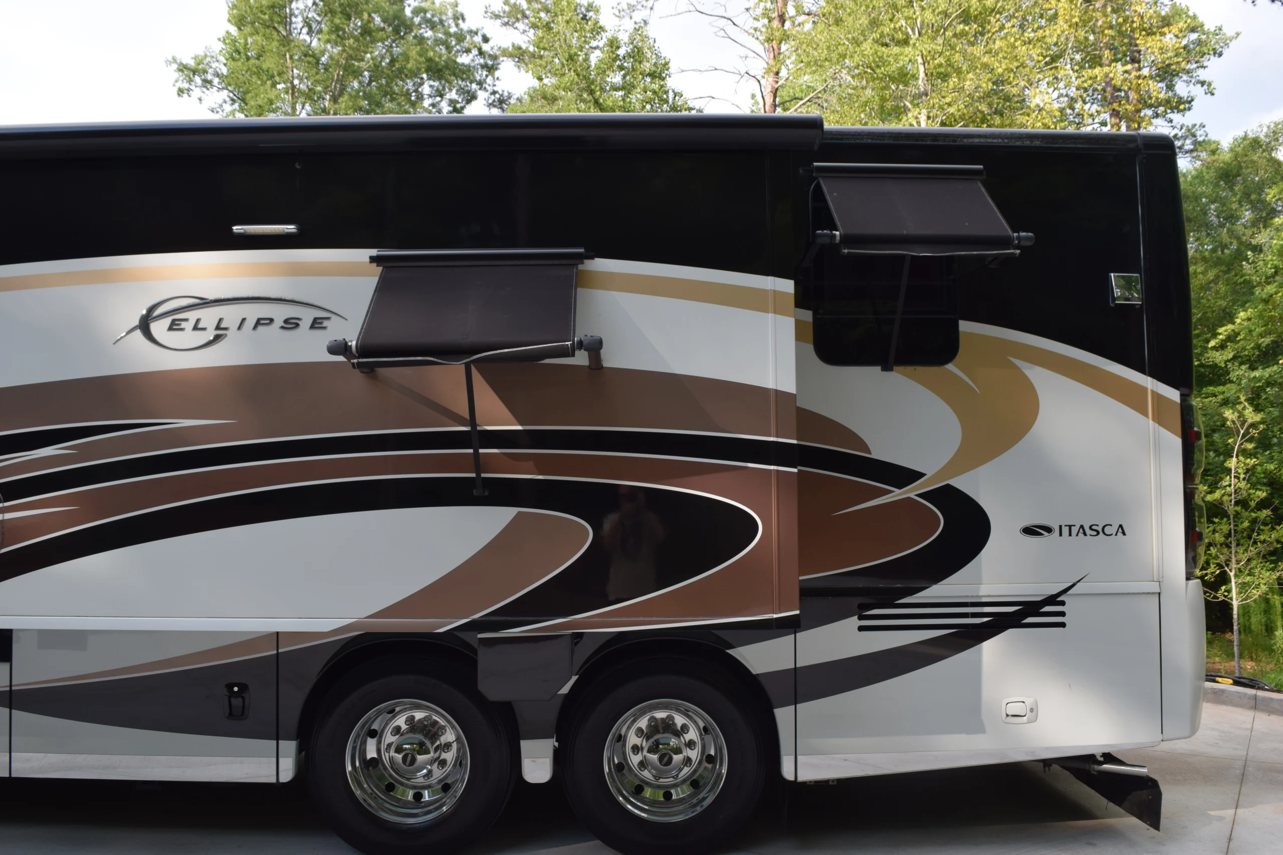 DSC_0567 Side view of a Motorcoach featuring intricate swirl designs in brown and black, with windows partially covered by awnings.
