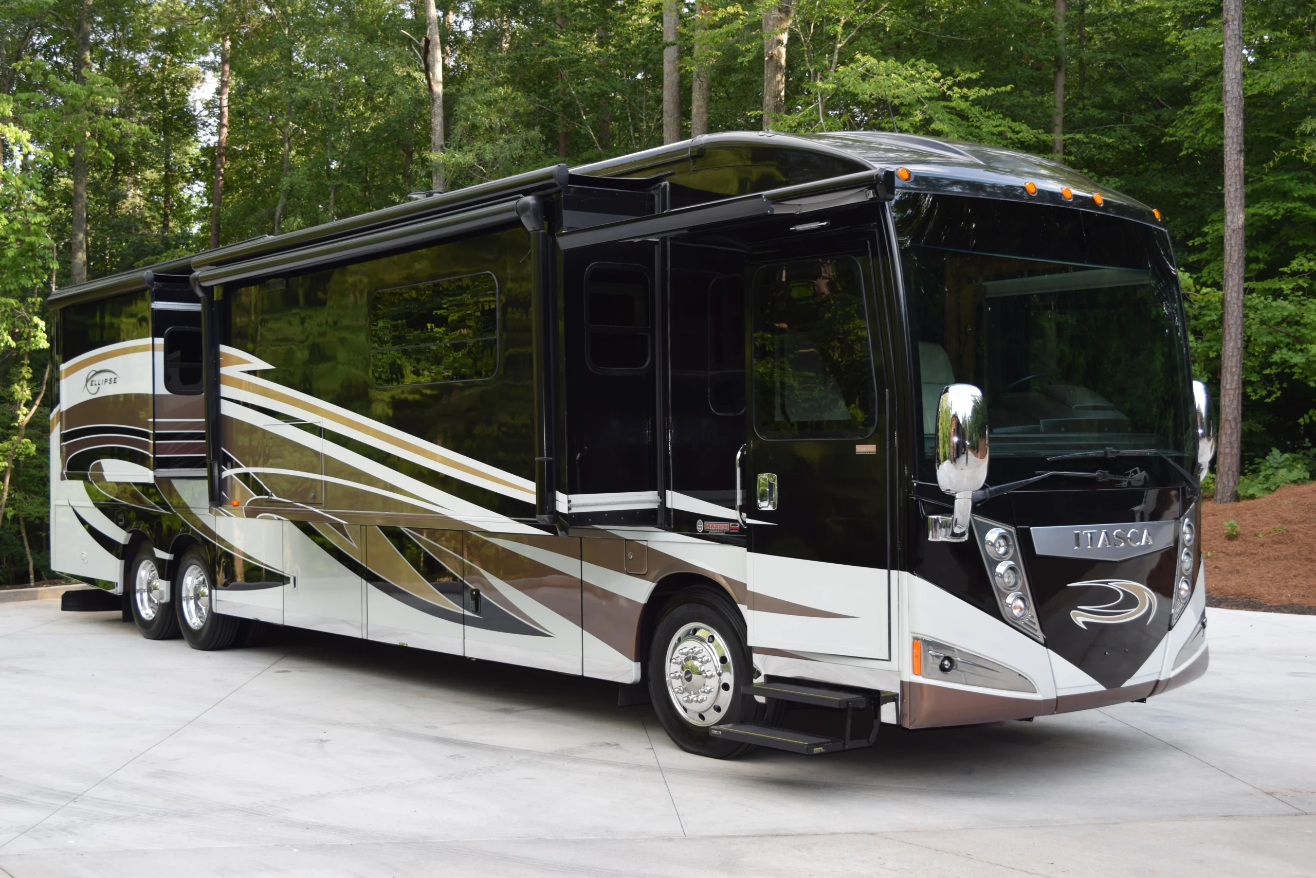 DSC_0574 Luxurious black and white motorcoach with modern design parked on a forested driveway, showcasing elegance and mobility.