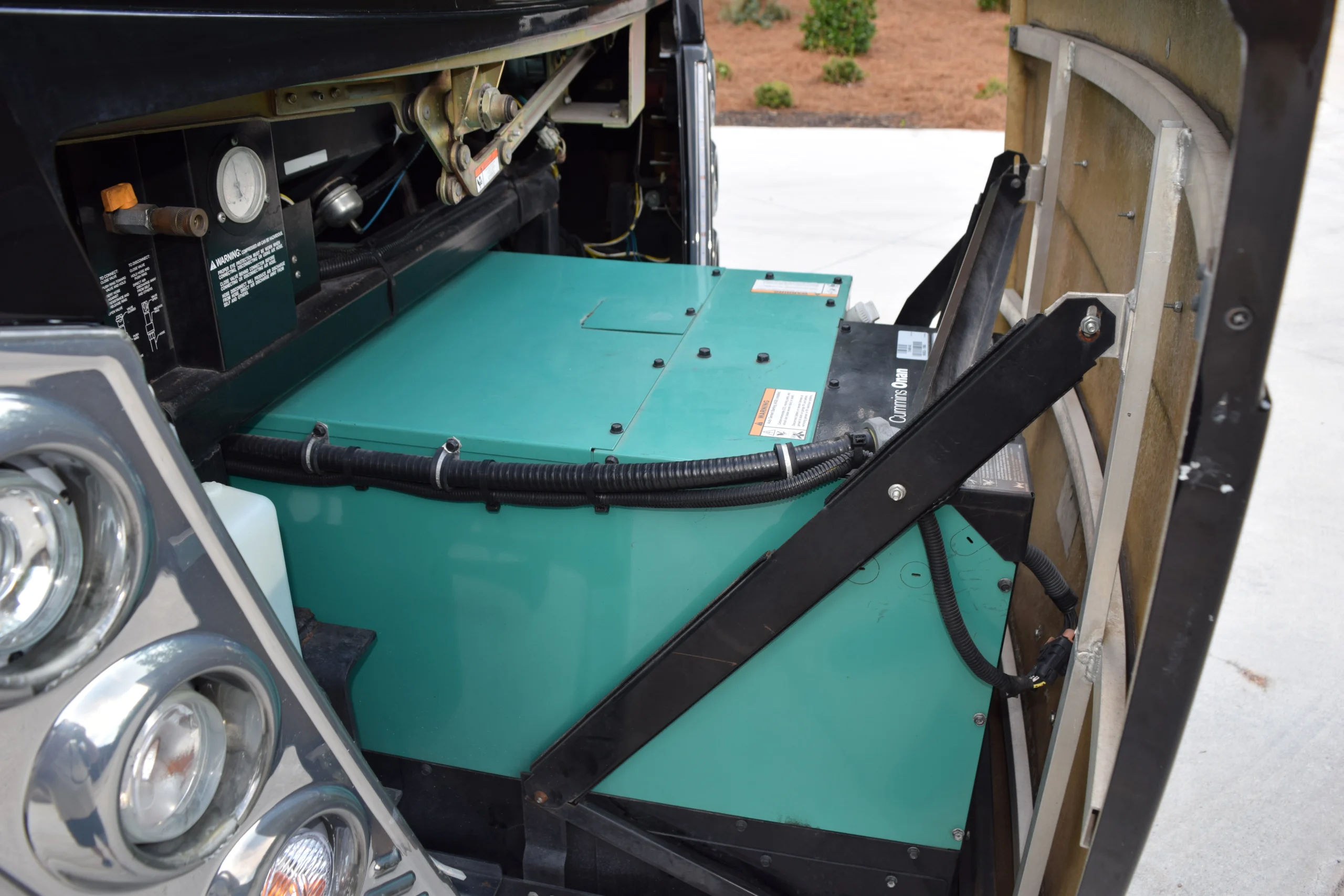 DSC_0577 Open compartment of a Motorcoach showing an Onan generator, wiring, and control panel.