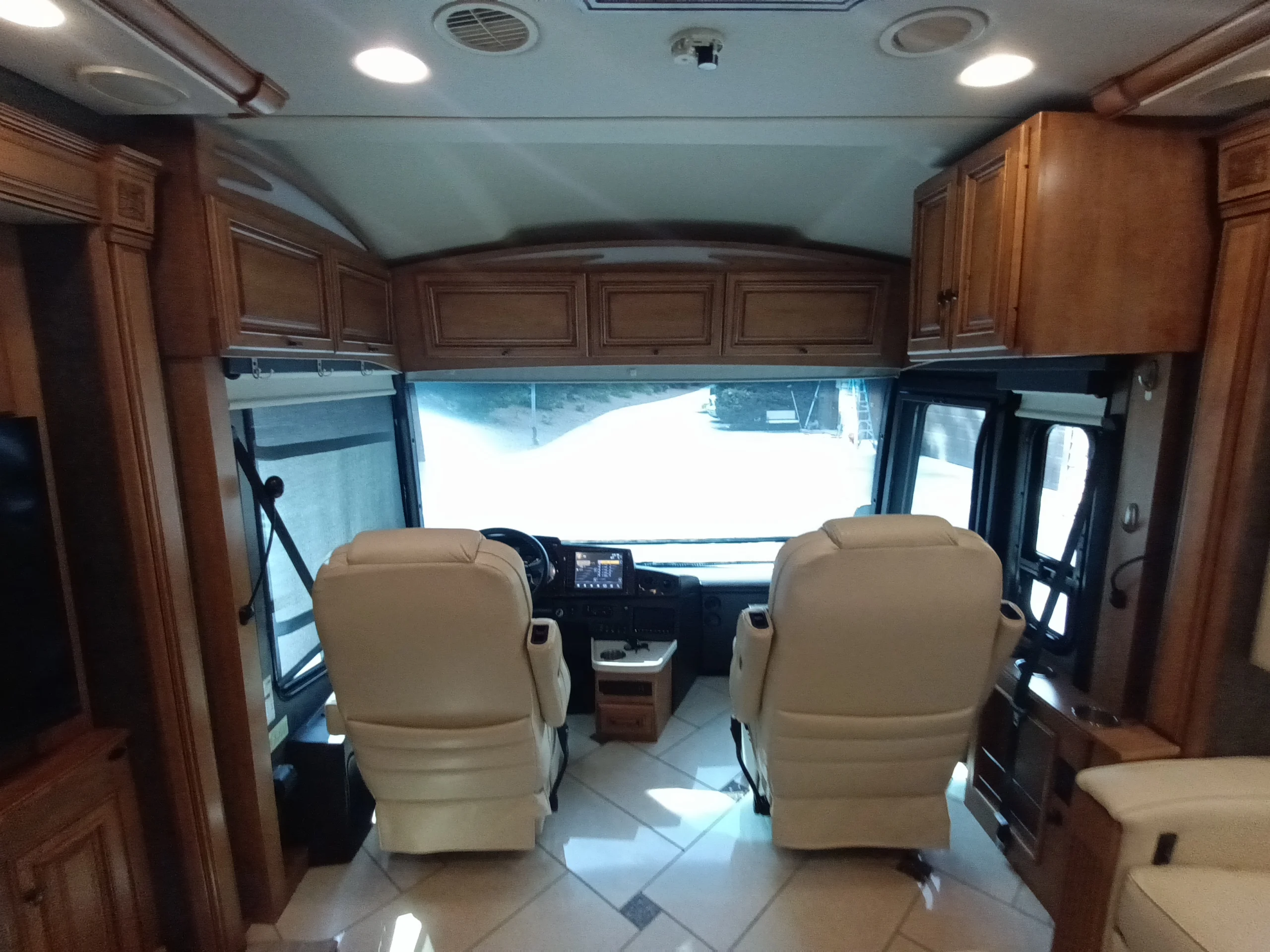 IMG_20260710_172032_378 Luxurious Motorcoach and RVs interior with plush captain seats, wooden cabinets, and modern dashboard, viewed from the living area.