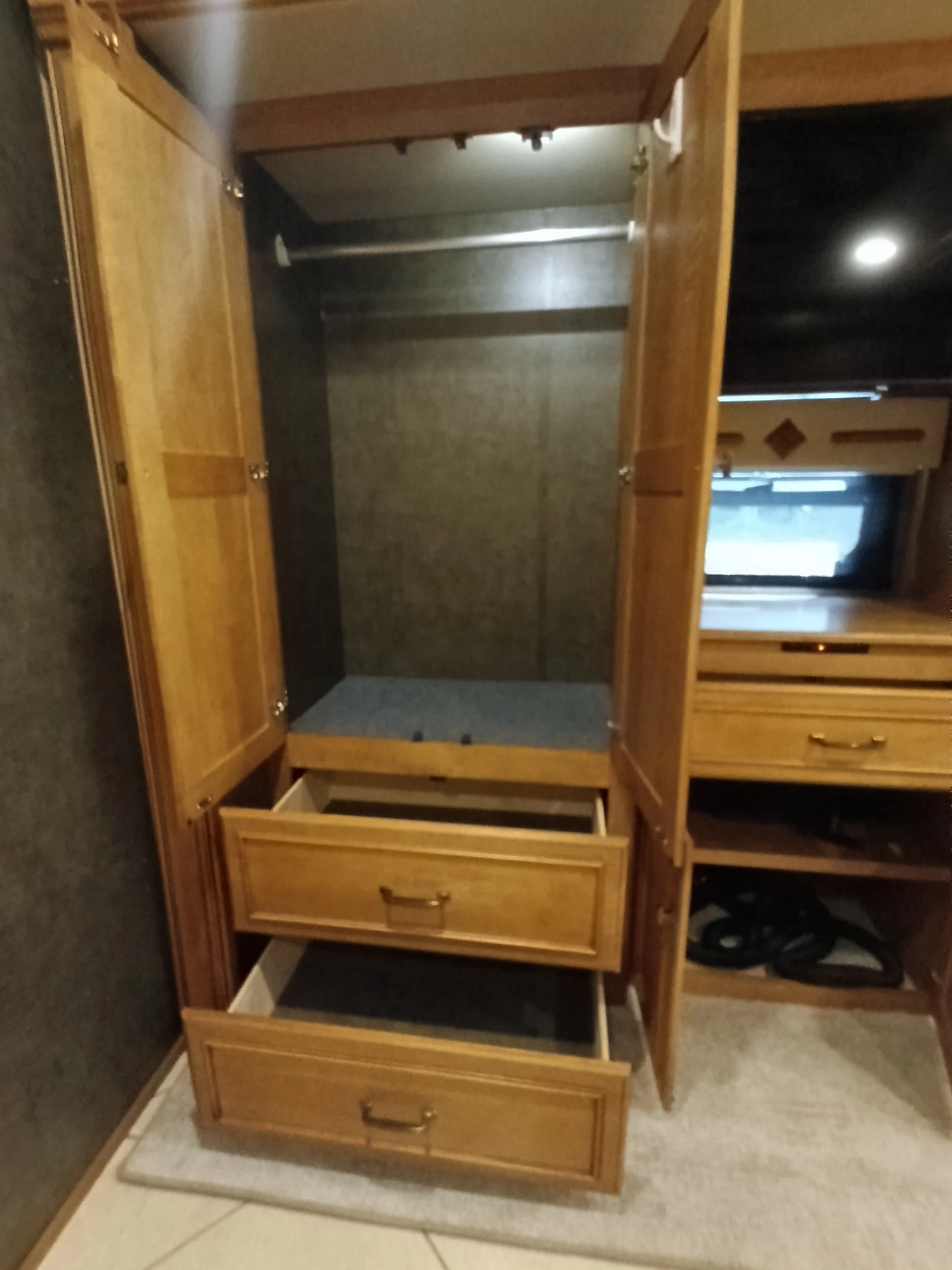 IMG_20260710_172510_781 Open wooden wardrobe in motorcoaches and RVs, with two drawers extended and an empty hanging space above.
