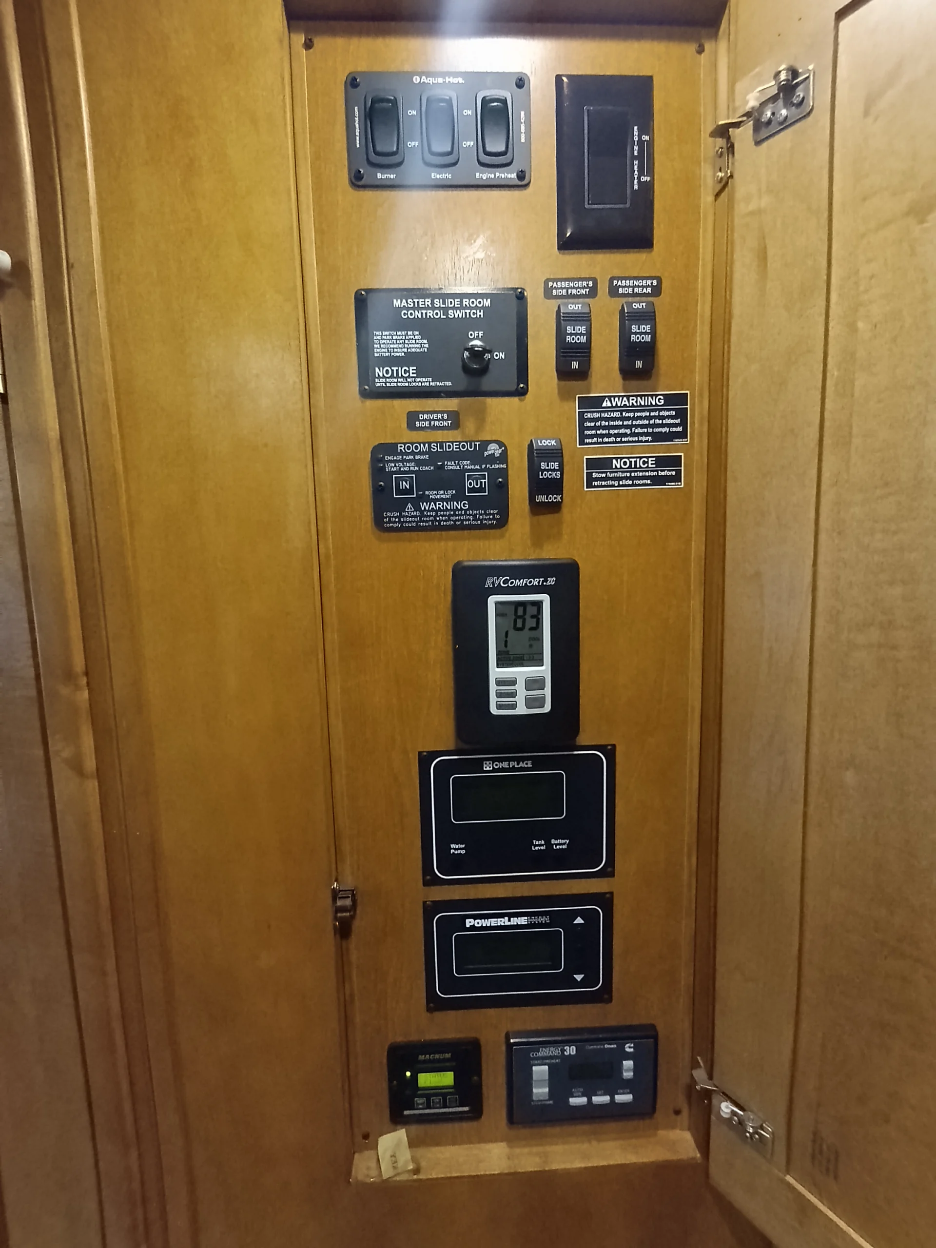 IMG_20260710_172657_695 Wooden control panel with various switches and digital displays for Motorcoach and RVs, including slide room controls and system monitors.