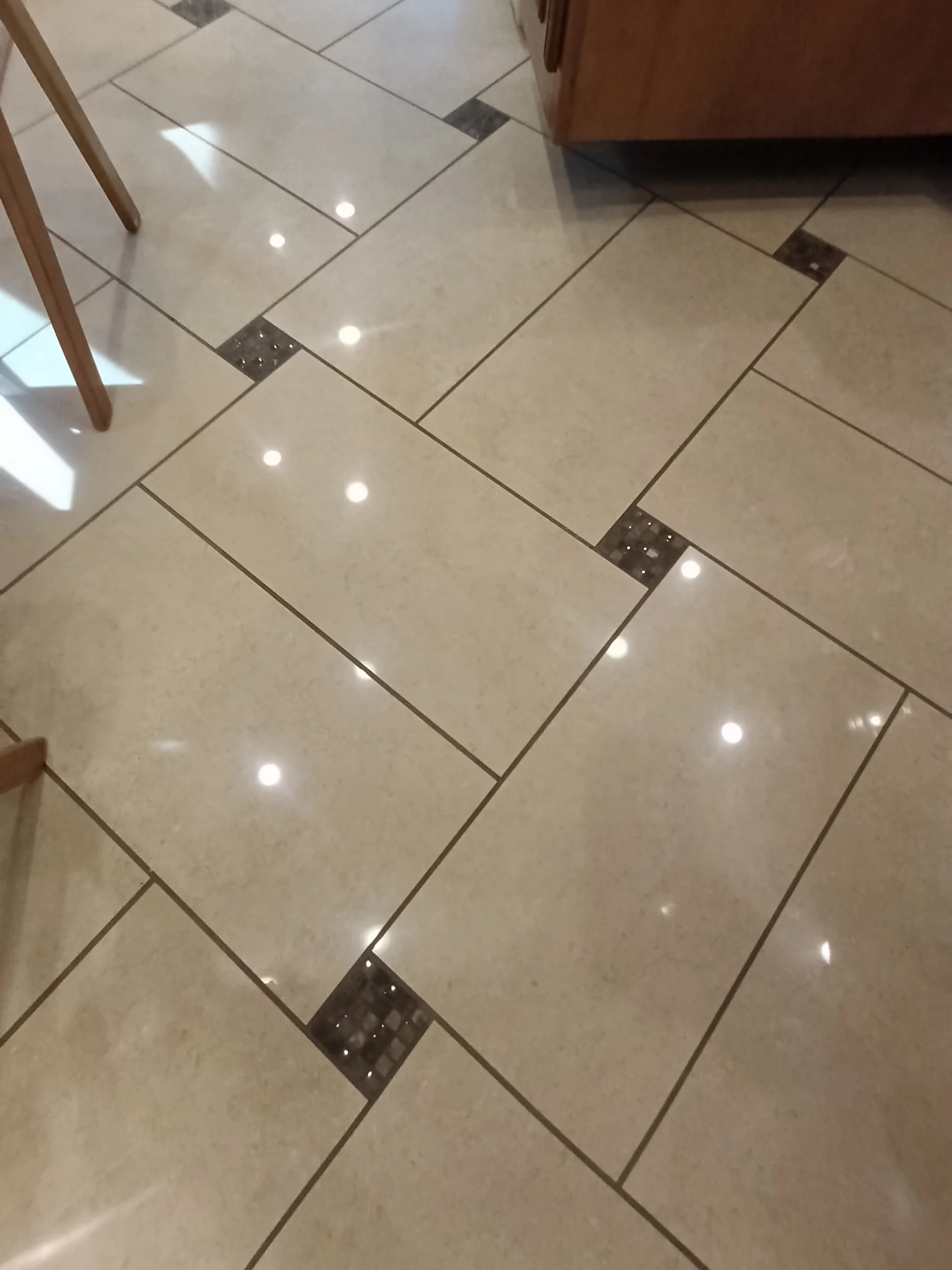 IMG_20260710_172749_618 Glossy beige tiled floor with reflective surface and dark square accents, typical in high-end motorcoach and RVs.