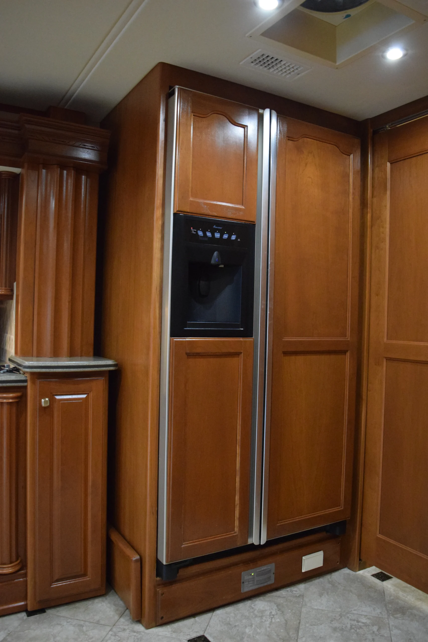 DSC_0176 Wood-paneled refrigerator with a built-in water dispenser in a Motorcoach and RVs interior kitchen setting.