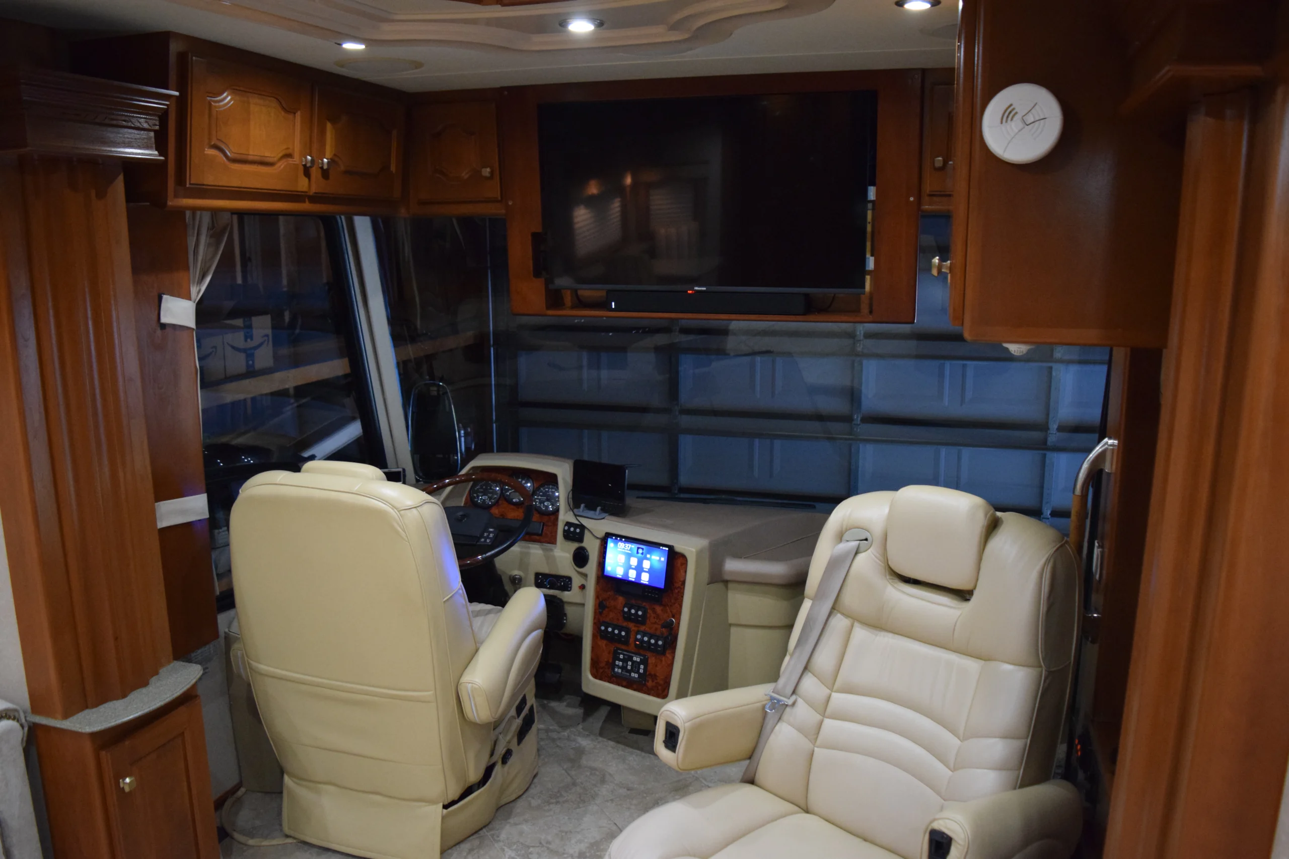 DSC_0209 Luxurious Motorcoach cockpit with leather seats, wood cabinets, large screen, and control panel, highlighting a modern RV interior.