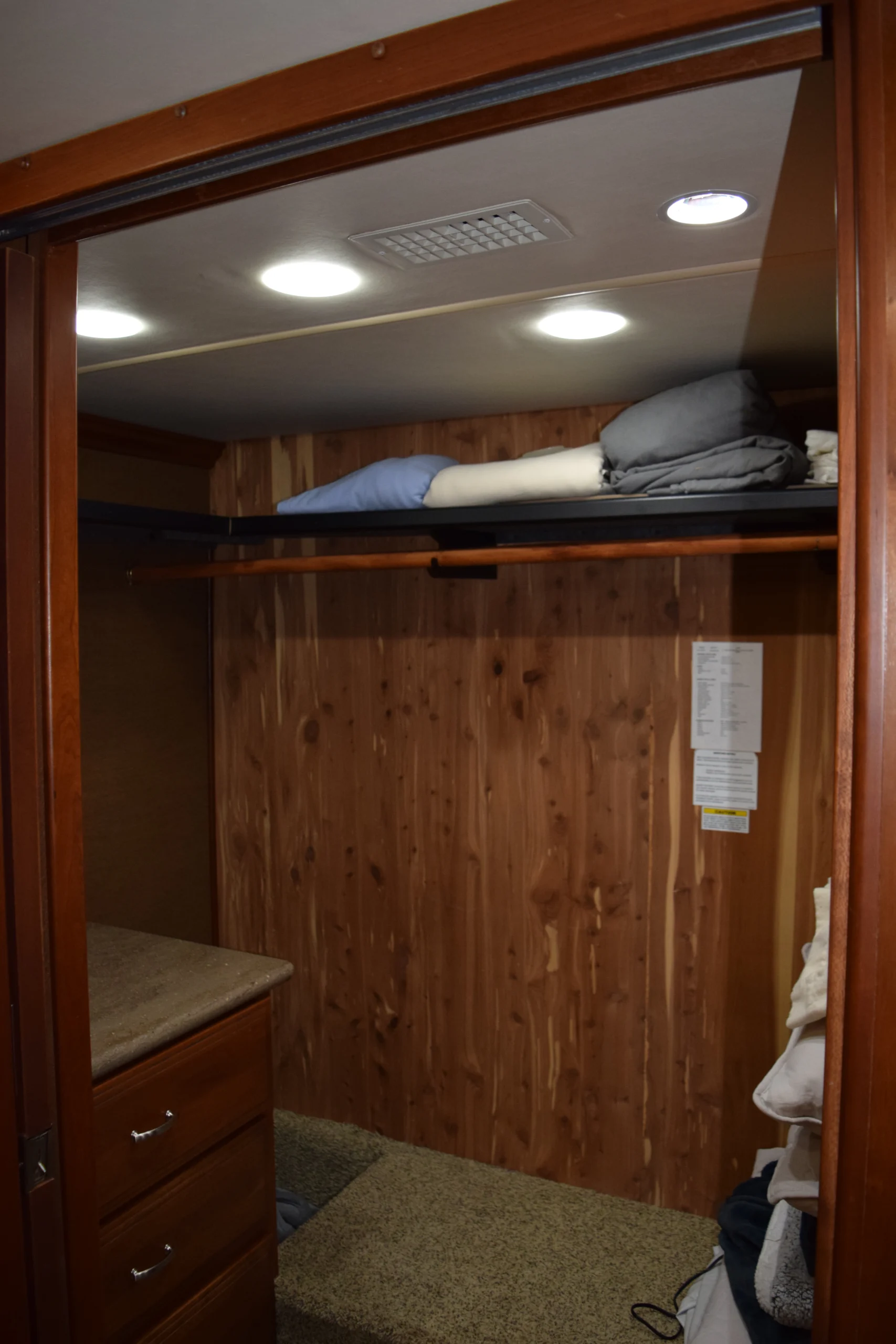 DSC_0341 Wooden closet interior with folded linens on a shelf, beneath recessed lighting. Ideal storage in Motorcoach and RVs.