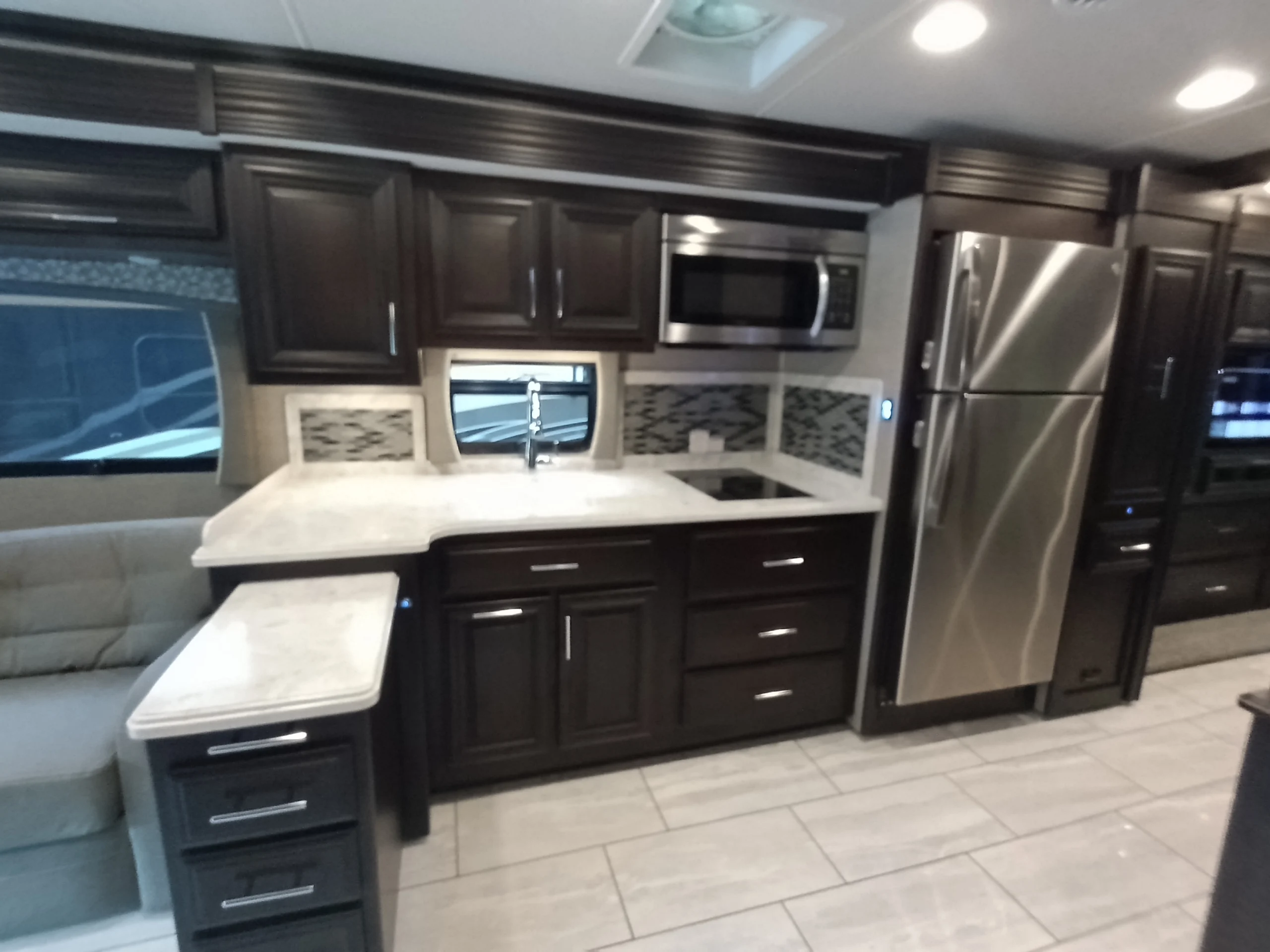IMG_20260611_191144_116 Spacious Motorcoach kitchen with dark wood cabinets, stainless steel appliances, and marble countertops.