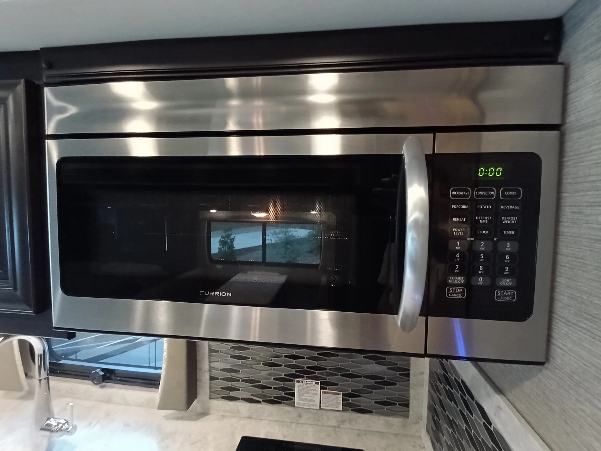 IMG_20260611_191359_542 Stainless steel microwave with digital display, located above a backsplash and sink in a Motorcoach and RVs interior kitchen.