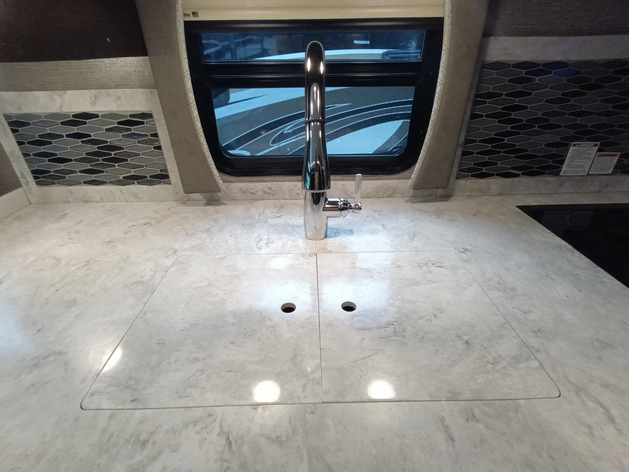 IMG_20260611_191409_845 Modern countertop with a sleek faucet and integrated sink cover in a Motorcoach and RVs interior kitchen.