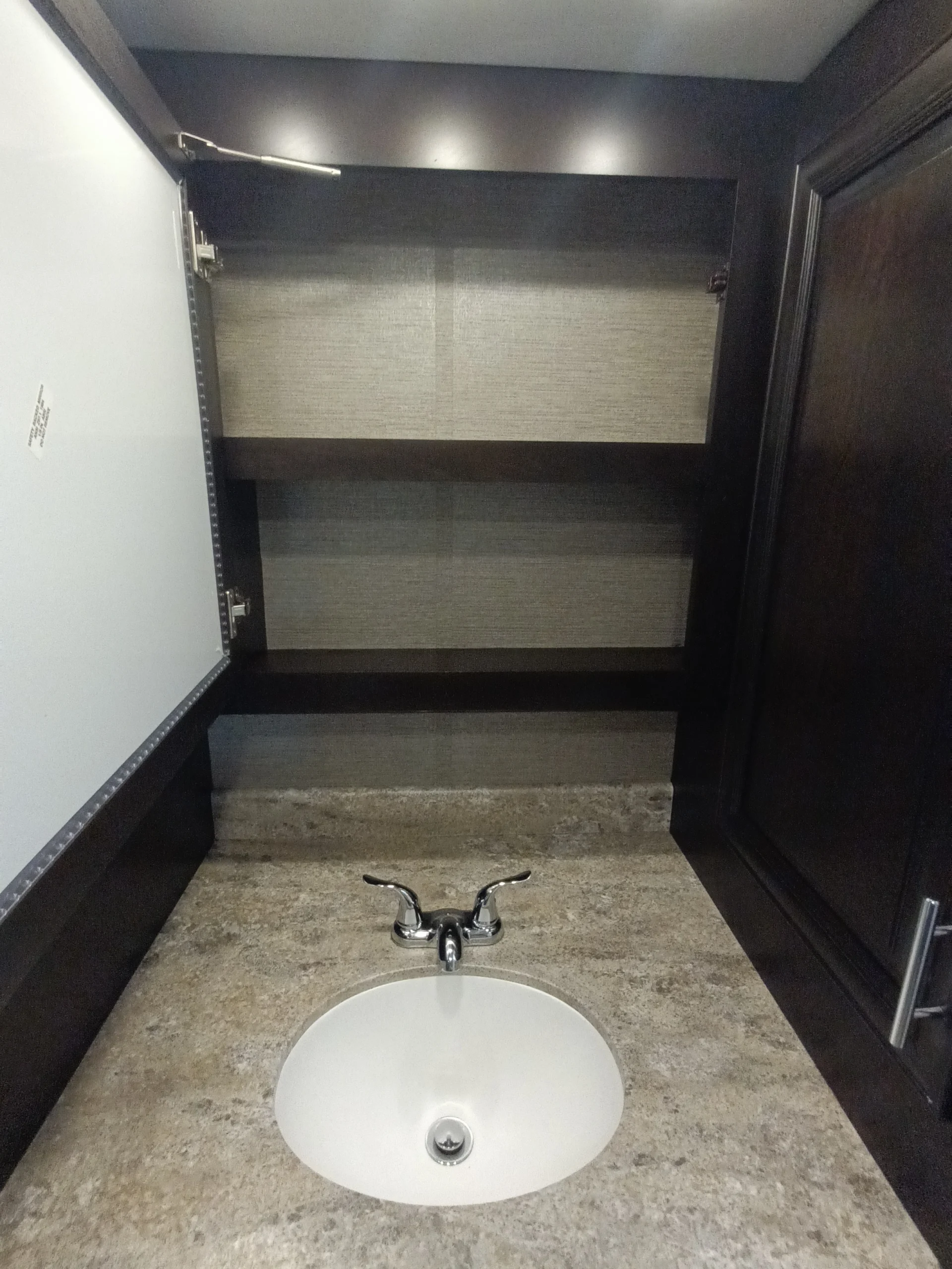 IMG_20260611_192038_487 RV bathroom interior with open medicine cabinet, modern faucet, and stone countertop. Ideal for Motorcoach and Rvs.