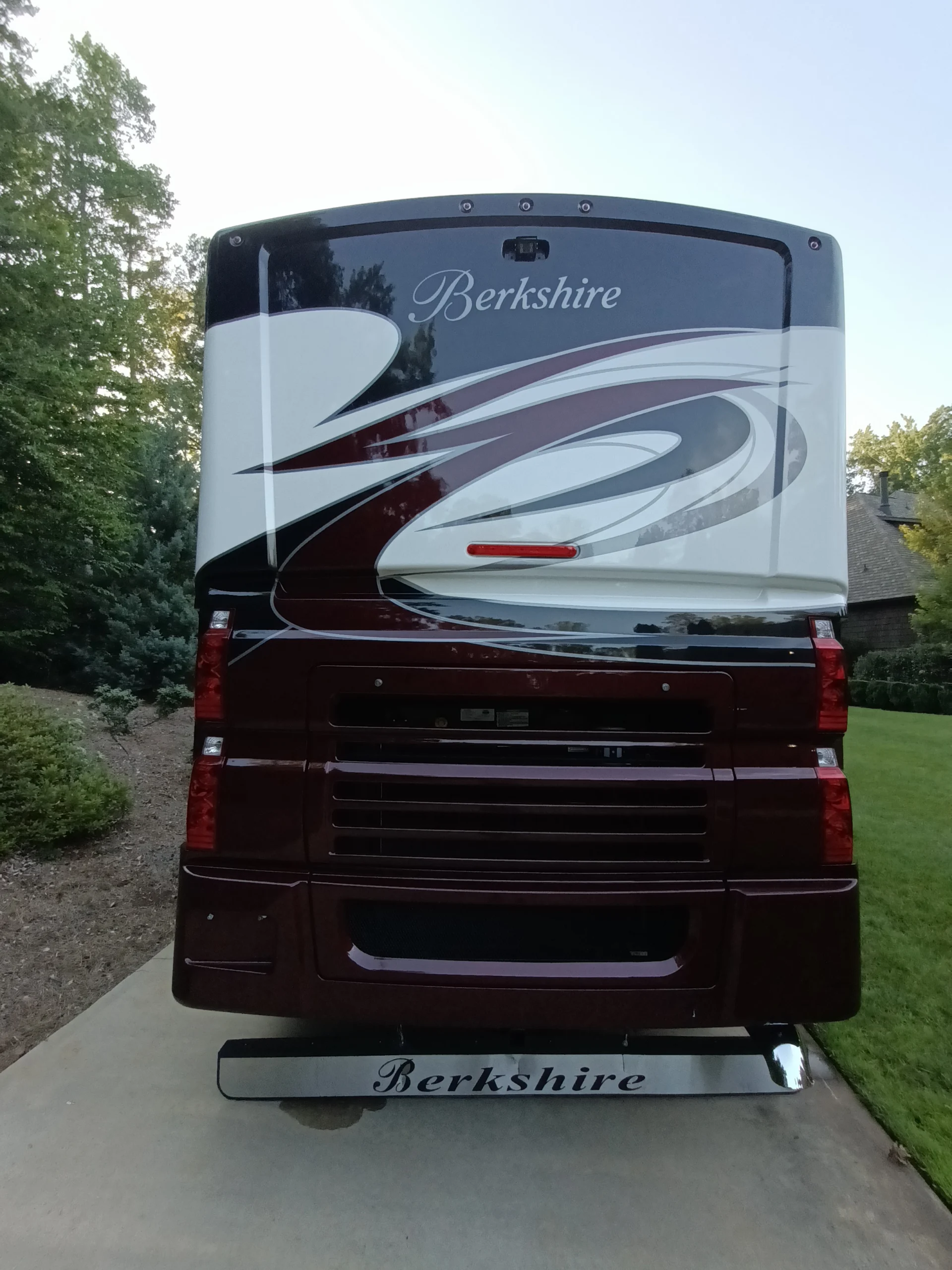 IMG_20260611_194147_165 Rear view of a Berkshire Motorcoach RV parked on a driveway, featuring sleek maroon and white design elements.