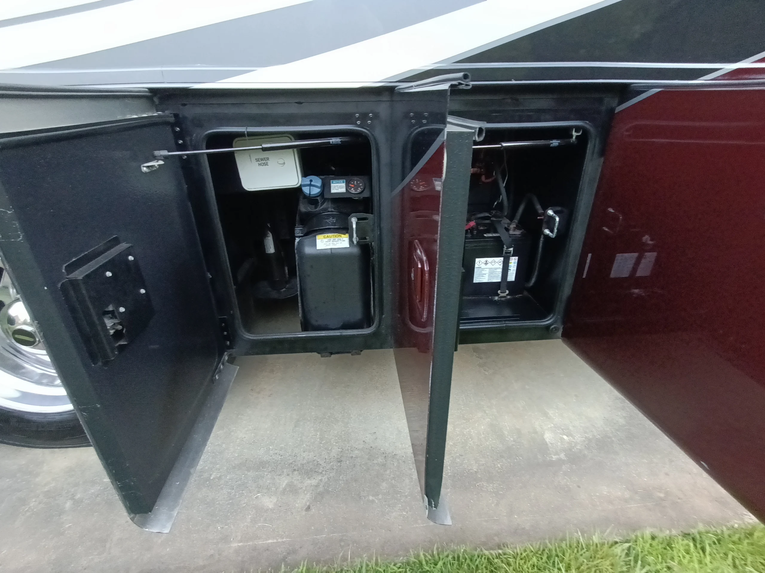 IMG_20260611_194722_336 Open storage compartments on a Motorcoach, revealing a water tank and battery system.
