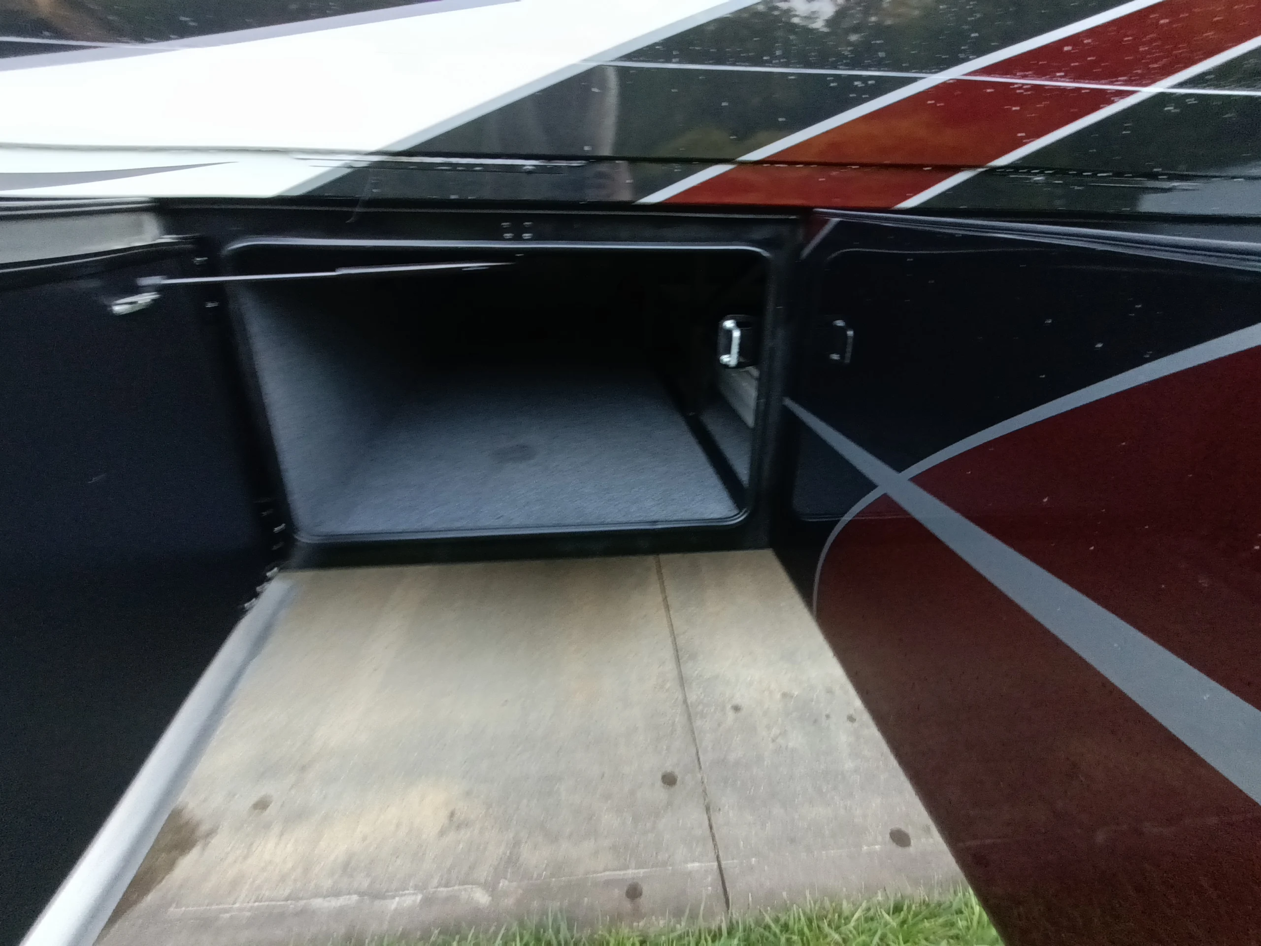 IMG_20260611_194759_822 Open storage compartment of a Motorcoach and RVs, showcasing ample interior space with gray lining and sleek exterior design.