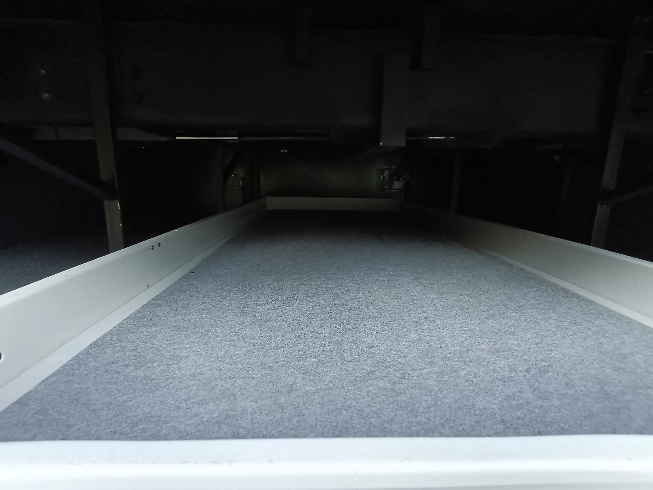 IMG_20260611_194818_555 Spacious storage compartment under a Motorcoach and RVs with a gray carpeted sliding tray for convenient access and organization.