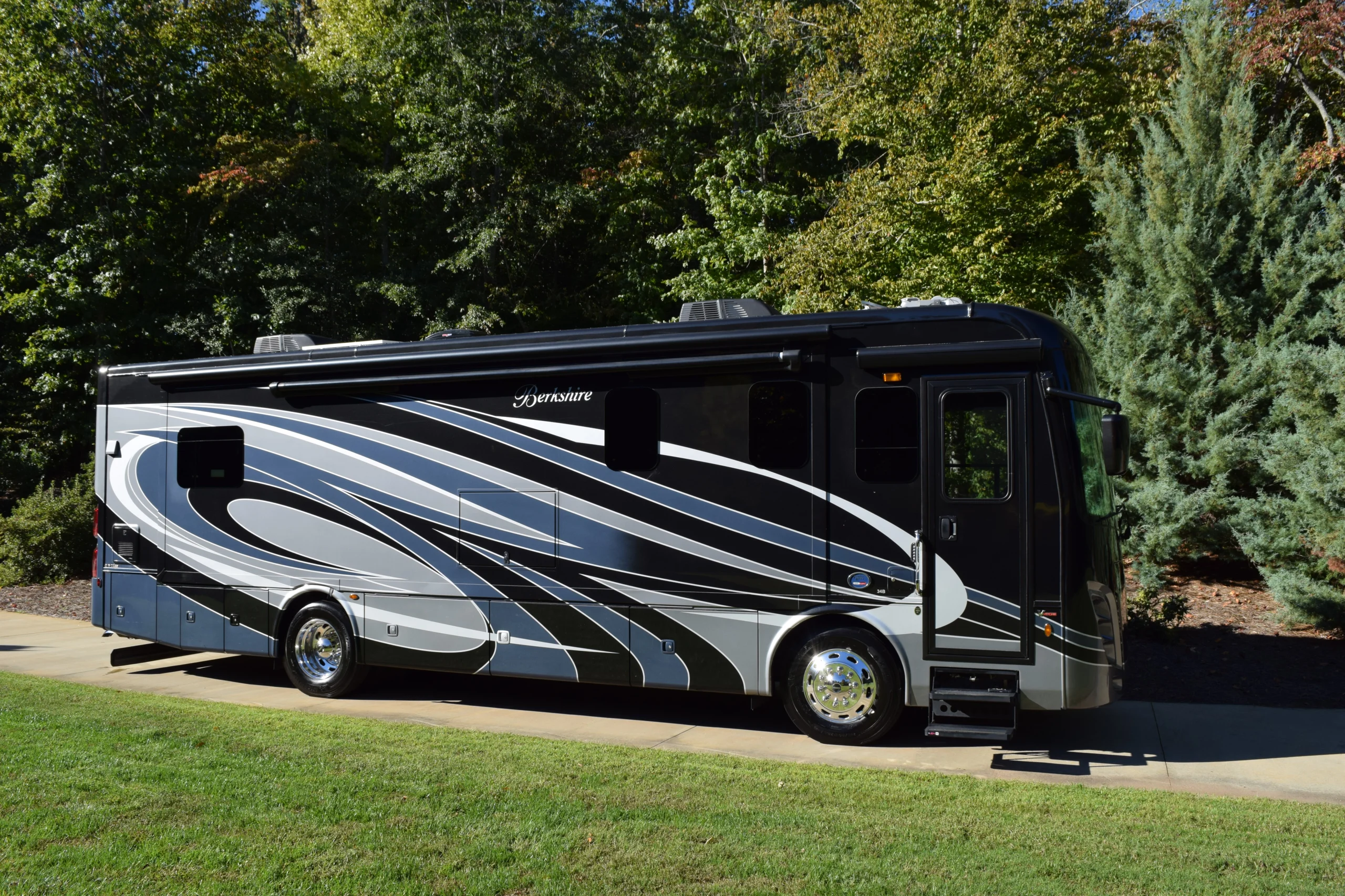 DSC_0689 Stylish black and silver motorcoach parked on a driveway, surrounded by lush greenery. Ideal for RV enthusiasts.