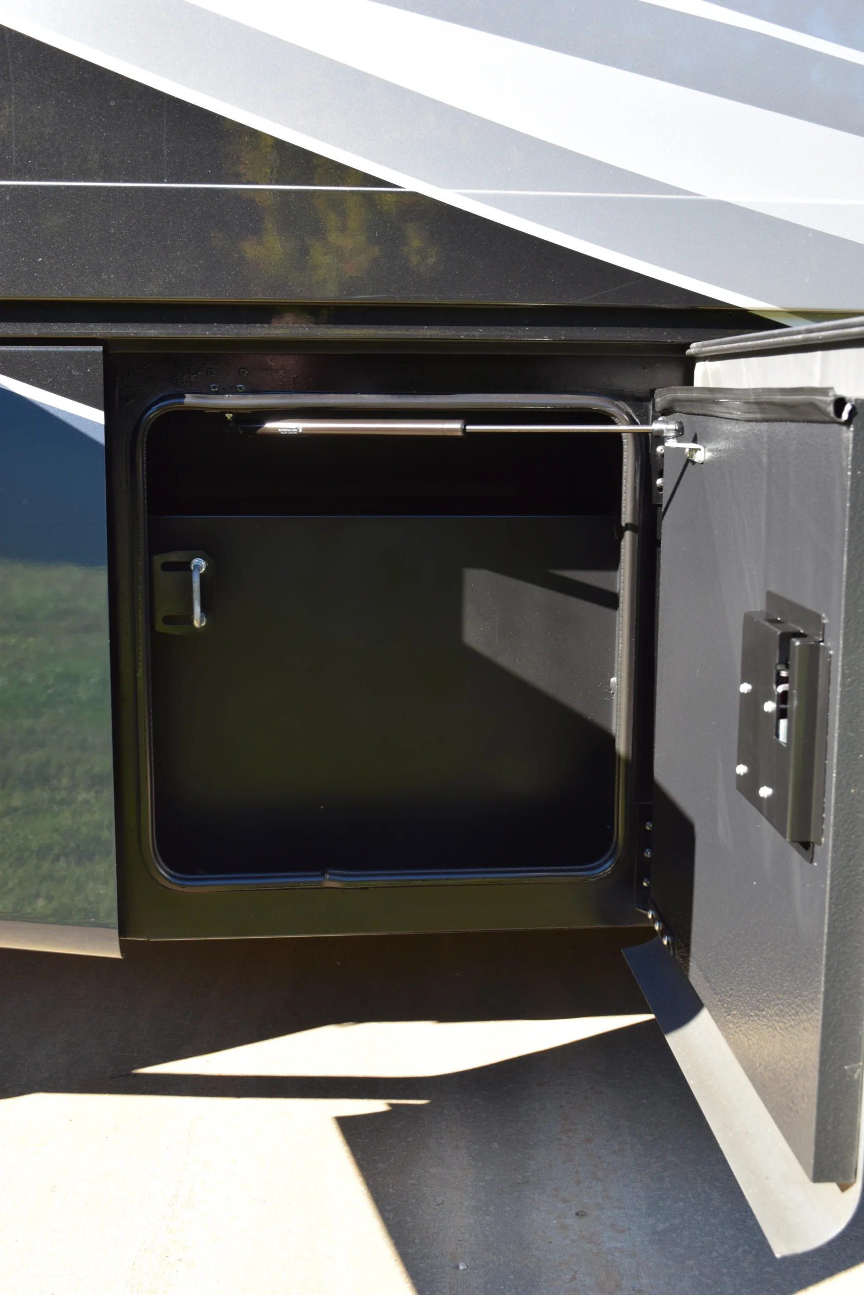 DSC_0702 Open storage compartment on a Motorcoach and Rvs, showcasing interior space and latch mechanism.