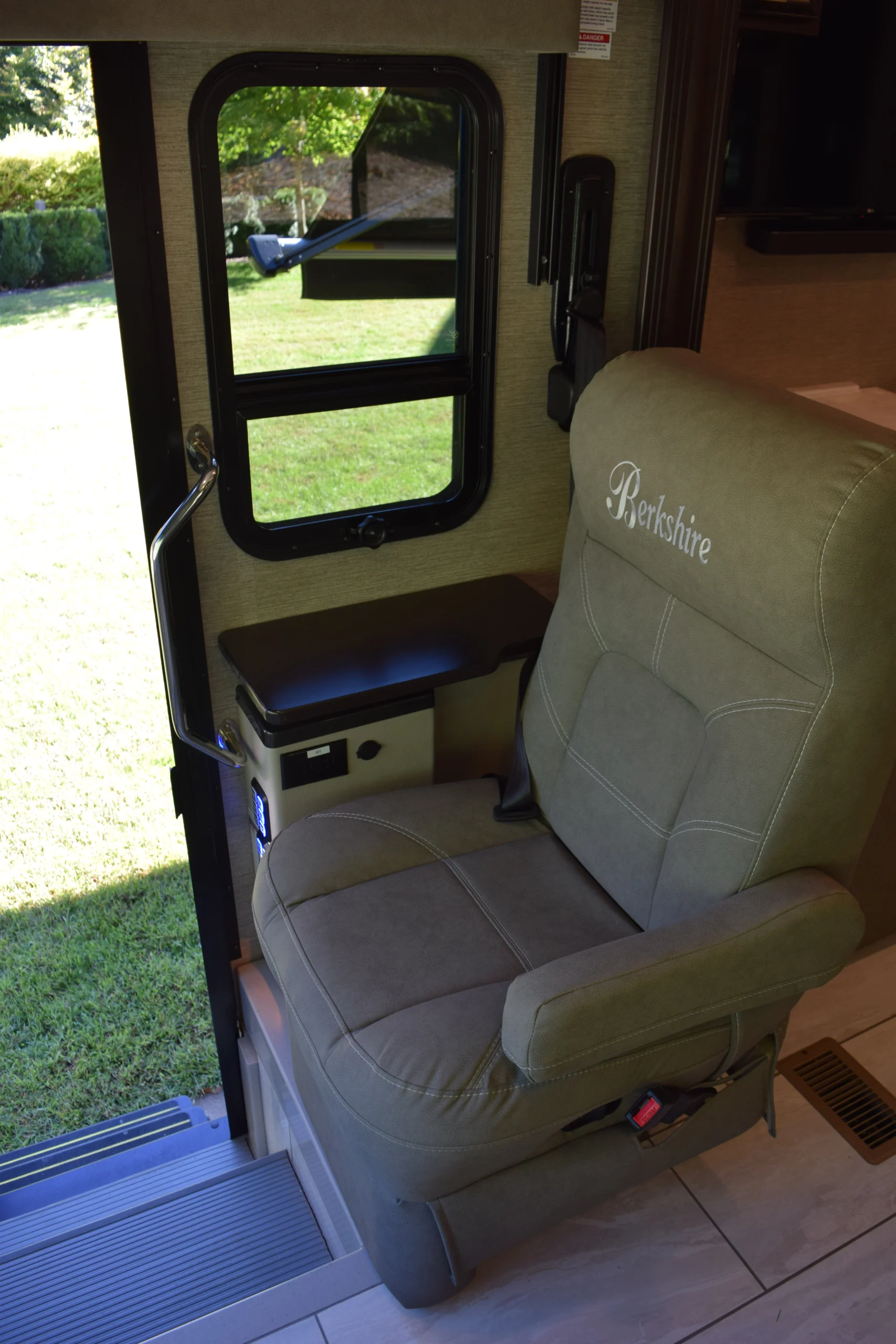 DSC_0724 Motorcoach interior featuring a tan seat labeled "Berkshire," next to a window with green grass visible outside.