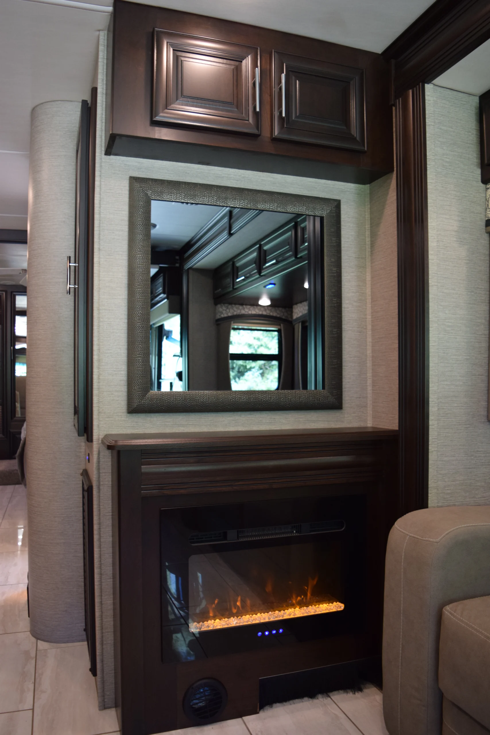 DSC_0729 Luxurious Motorcoach interior with dark wood cabinets, large mirror, and cozy electric fireplace, reflecting modern RV design.