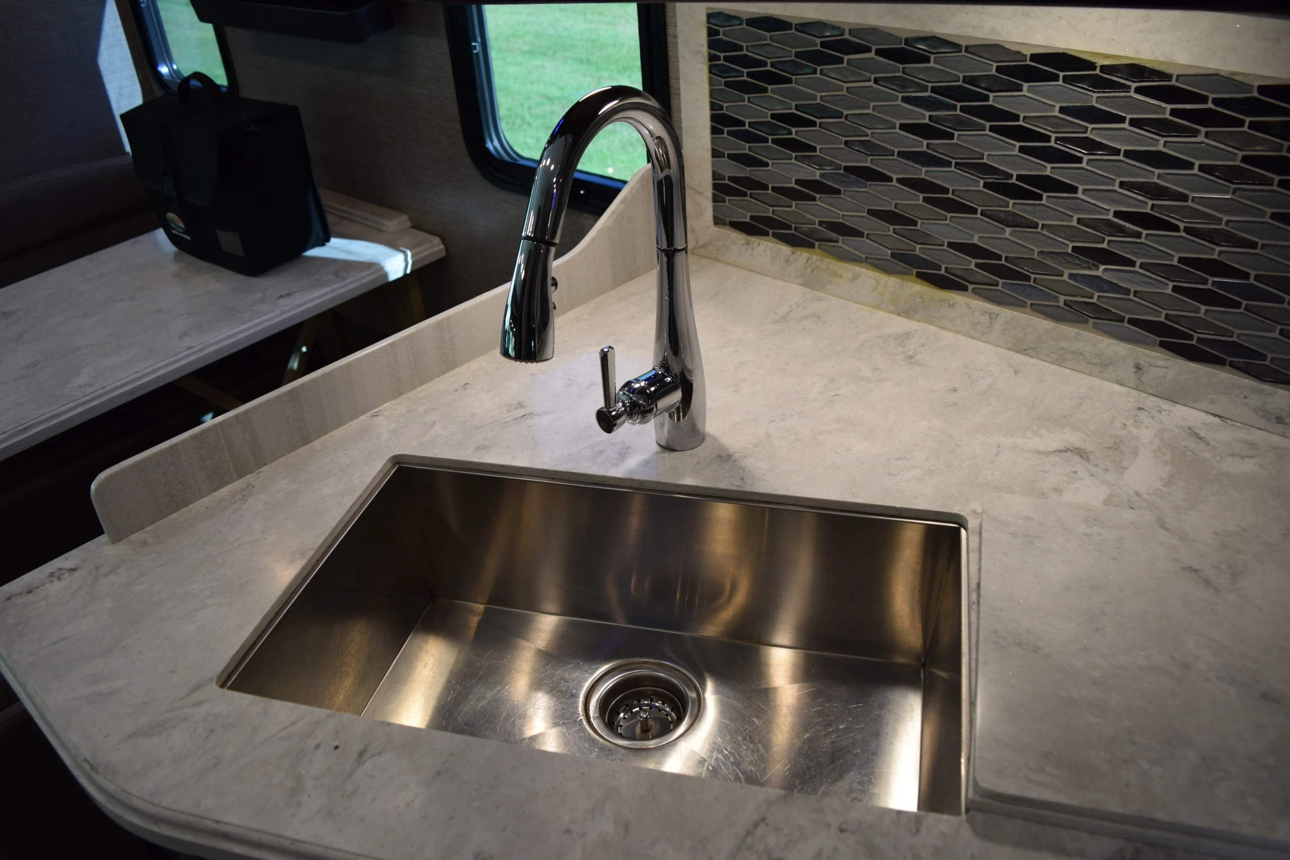 DSC_0739 Modern stainless steel sink and faucet in a Motorcoach and RV kitchen setting, with light countertop and patterned backsplash.