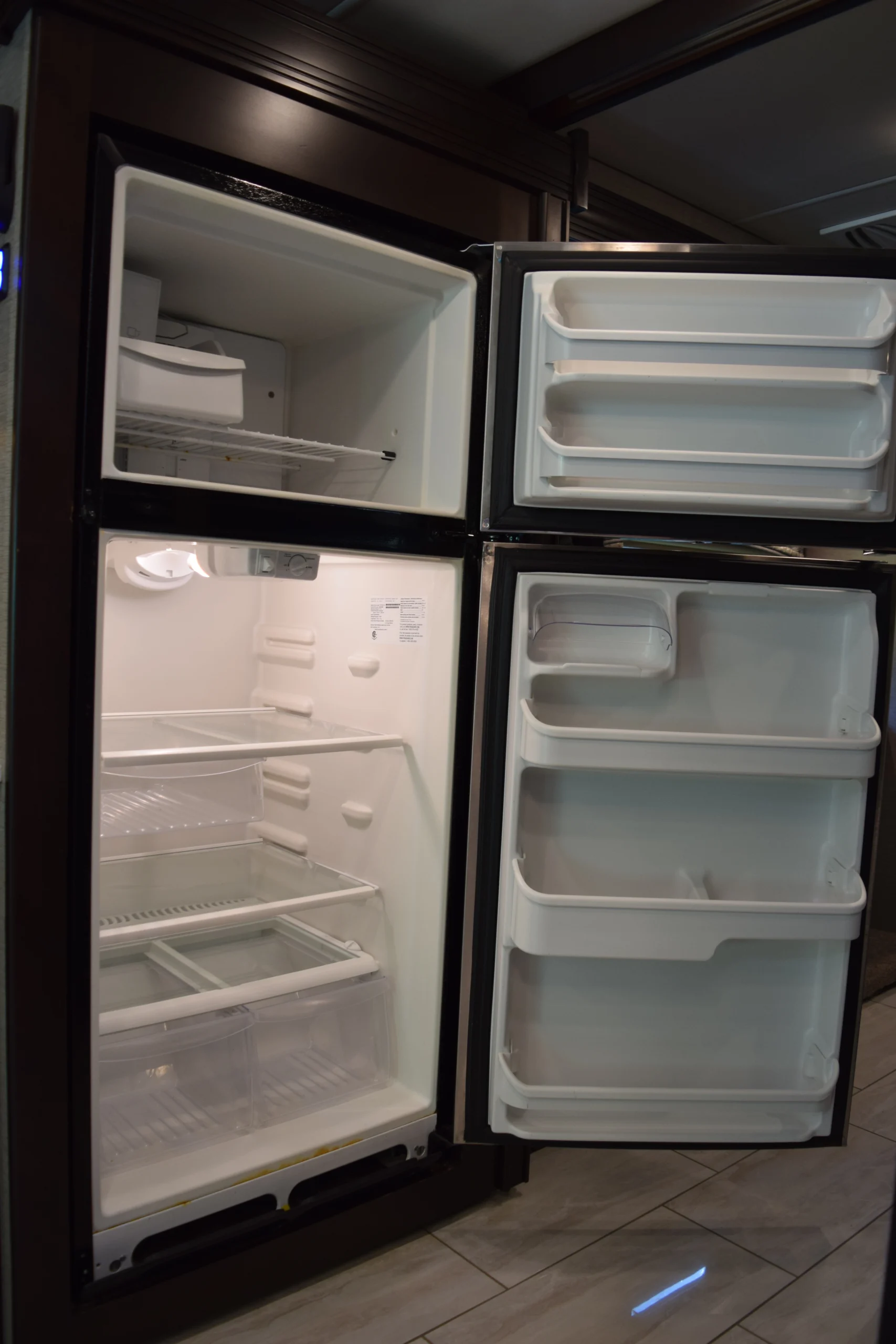 DSC_0745 Open fridge in a Motorcoach and RVs interior, featuring spacious freezer and fridge compartments with multiple door shelves.
