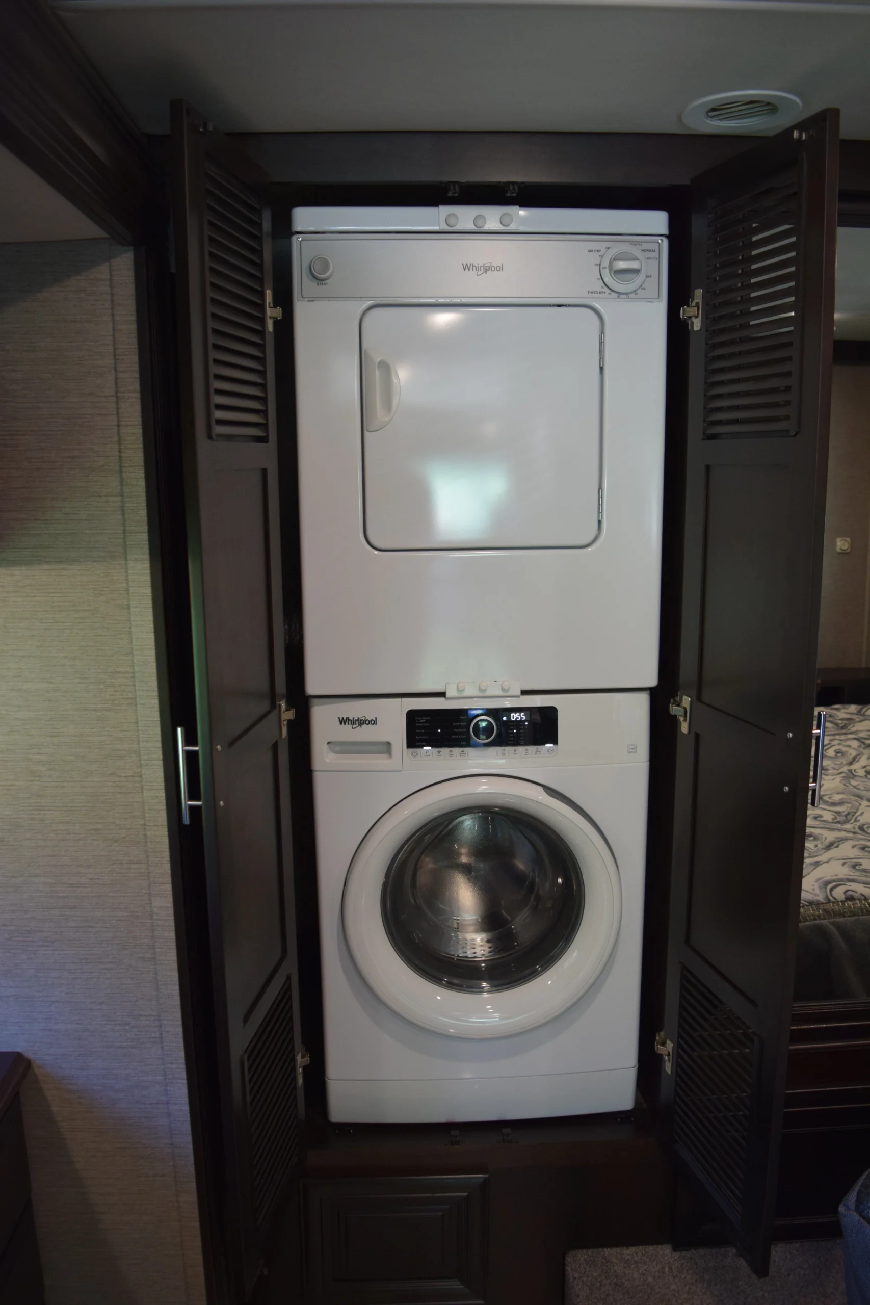 DSC_0748 Stacked washer and dryer inside a cabinet with open doors, common in motorcoach and RVs for compact convenience.