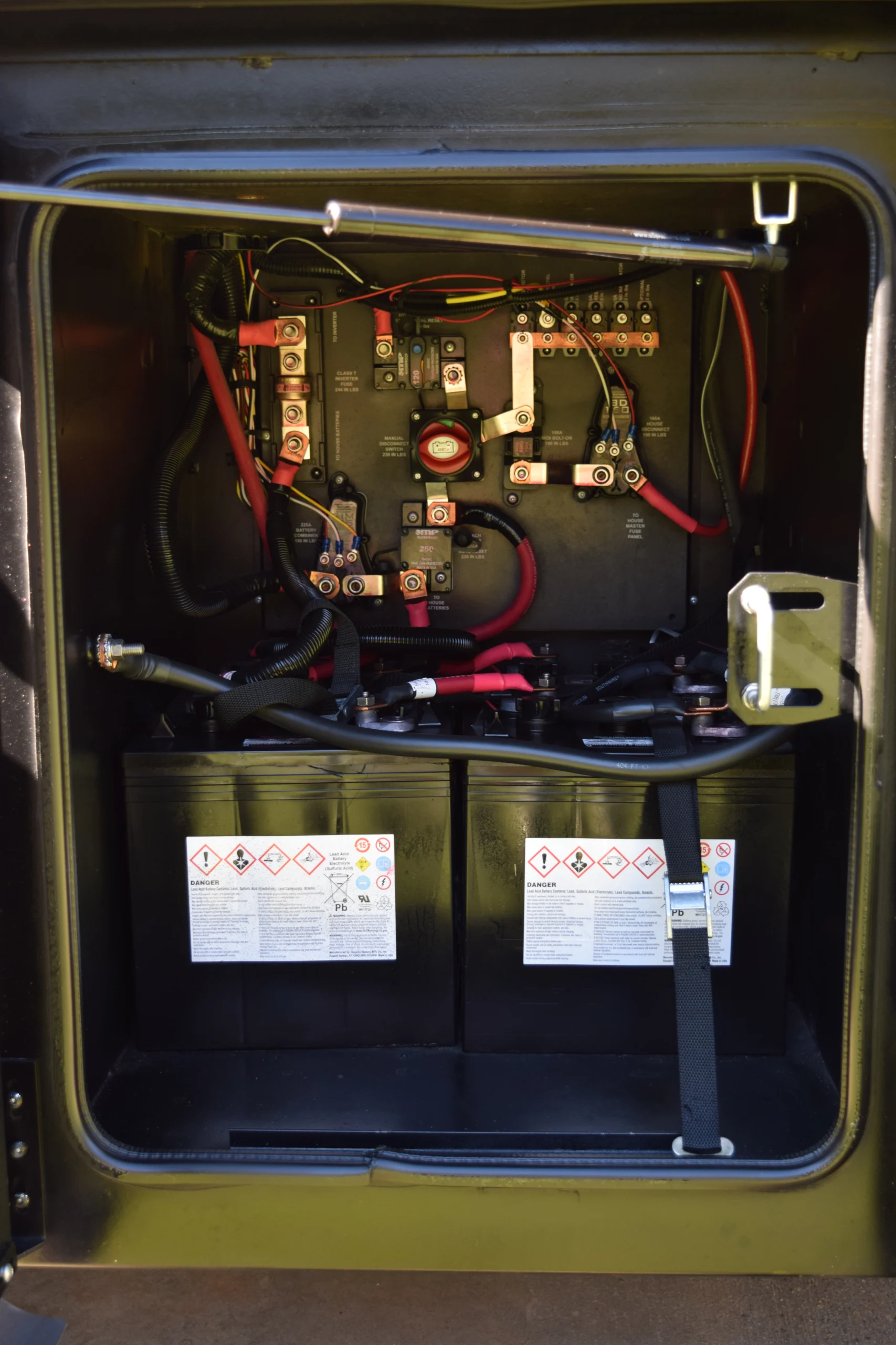 DSC_0771 Electrical panel in a Motorcoach and Rvs compartment, featuring circuit breakers, red and black wires, and labeled batteries.
