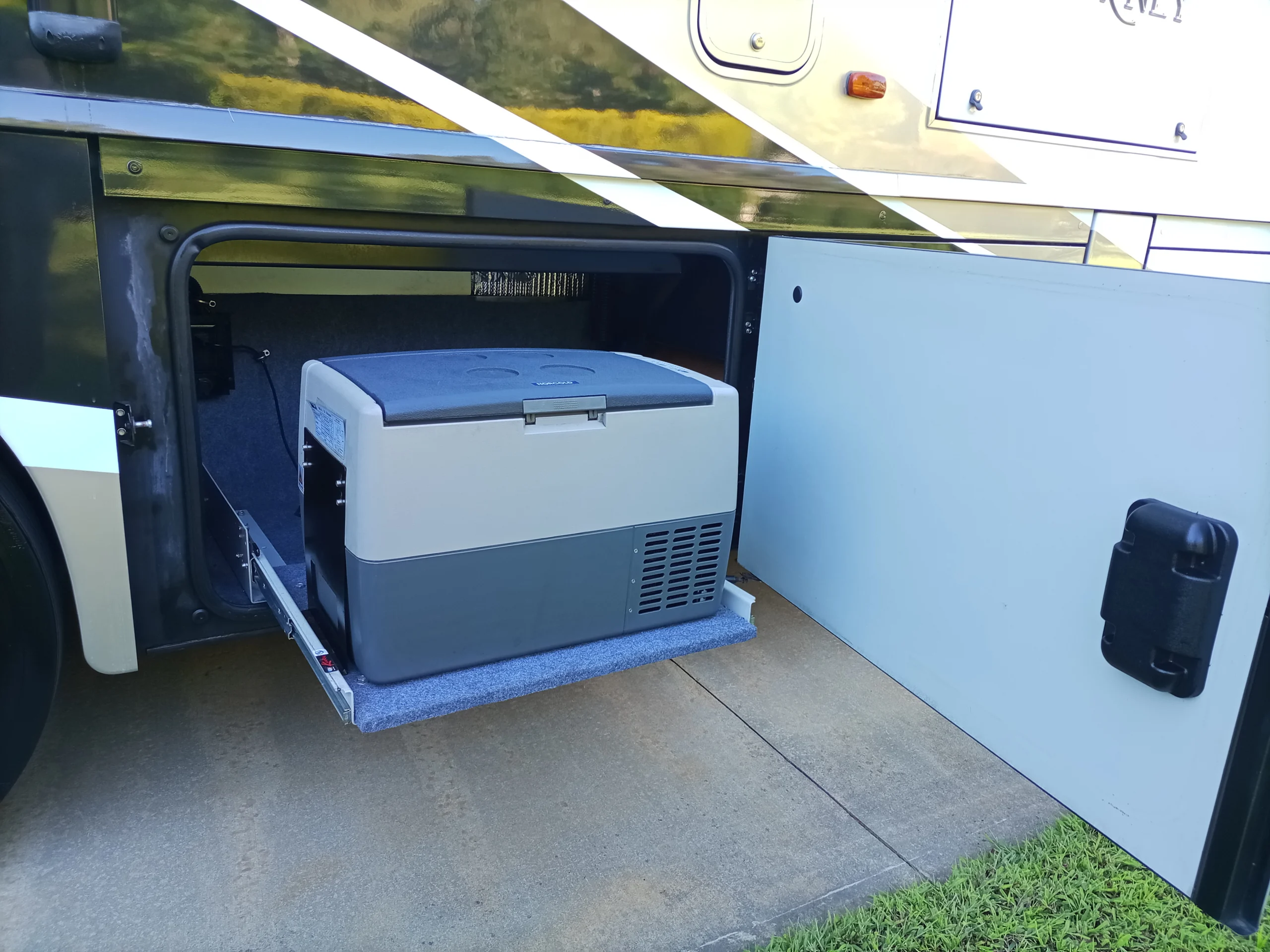 IMG_20260928_155914_715 RV with open storage compartment showing a portable fridge on a slide-out tray.