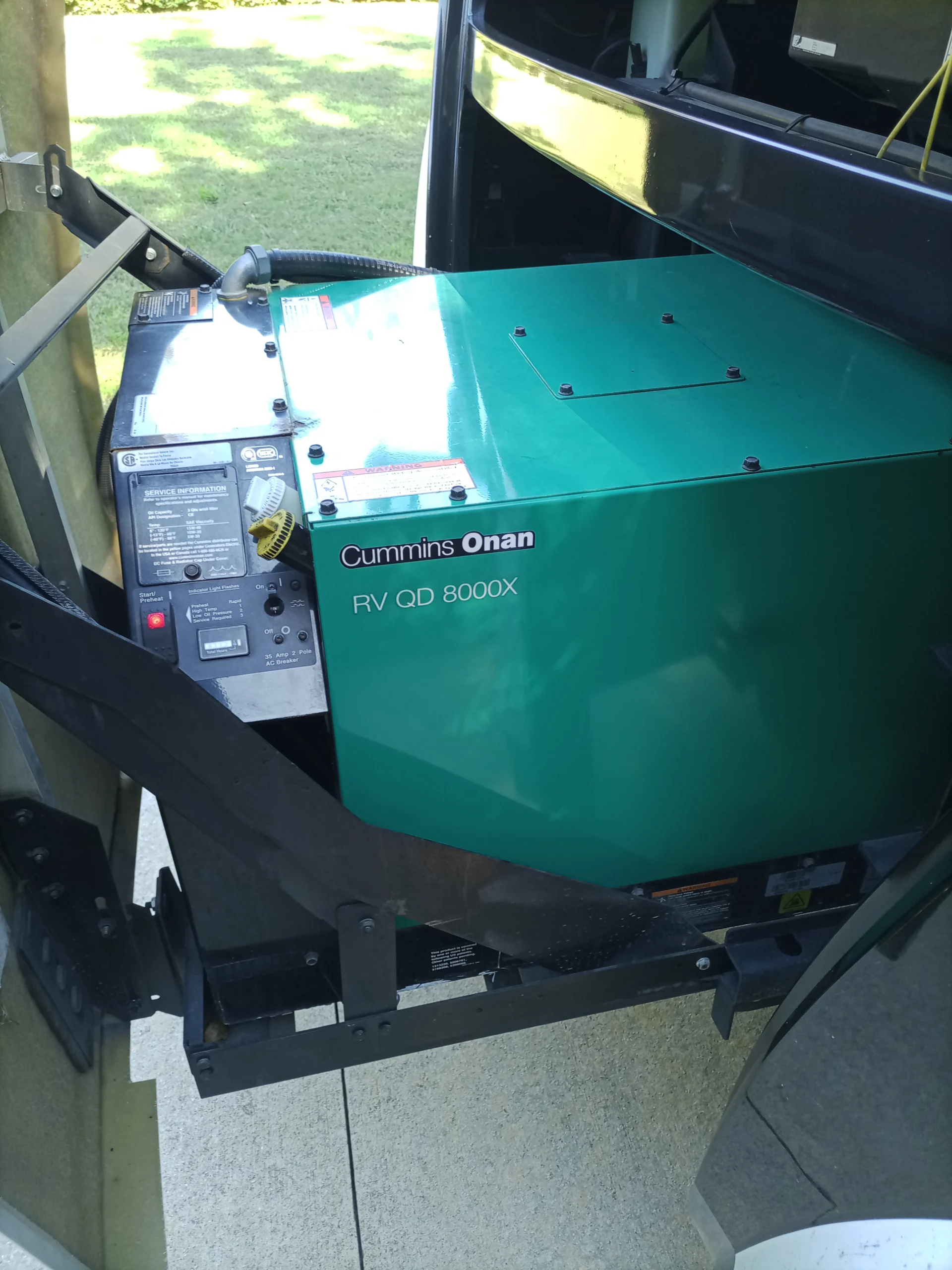 IMG_20260928_160404_516 Cummins Onan RV QD 8000X generator within a motorcoach. Green casing with control panel, mounted accessibly for RVs.